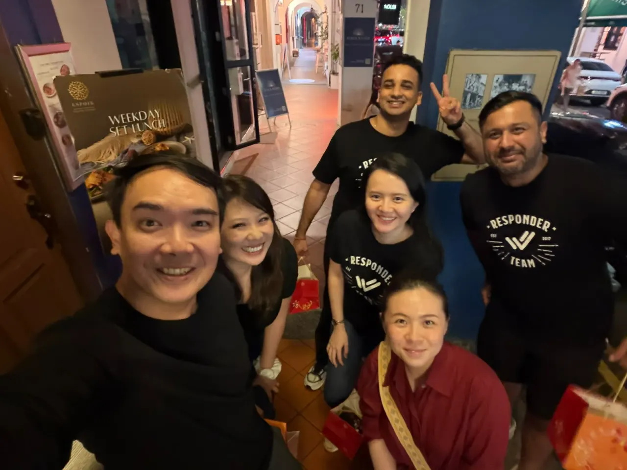 Ryan Chua and Stephanie Lim of Zelix Labs with the respond.io team, several wearing Responder Team t-shirts, on a Singapore street at night