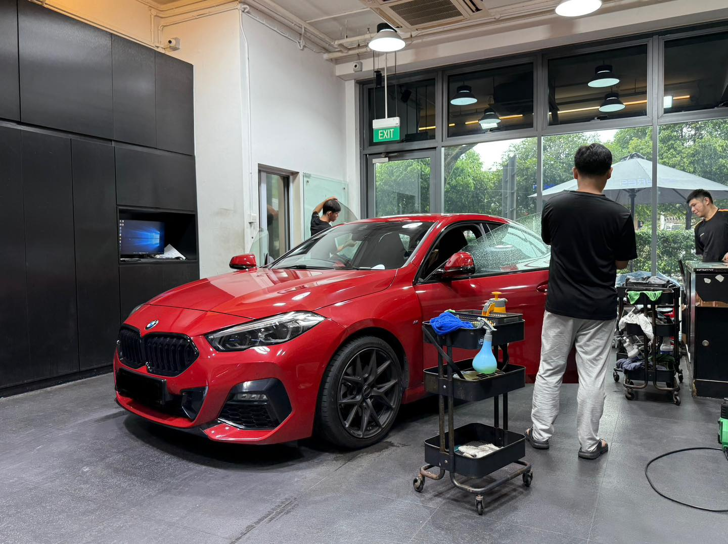 Infratint workshop with technicians installing window film on a red BMW
