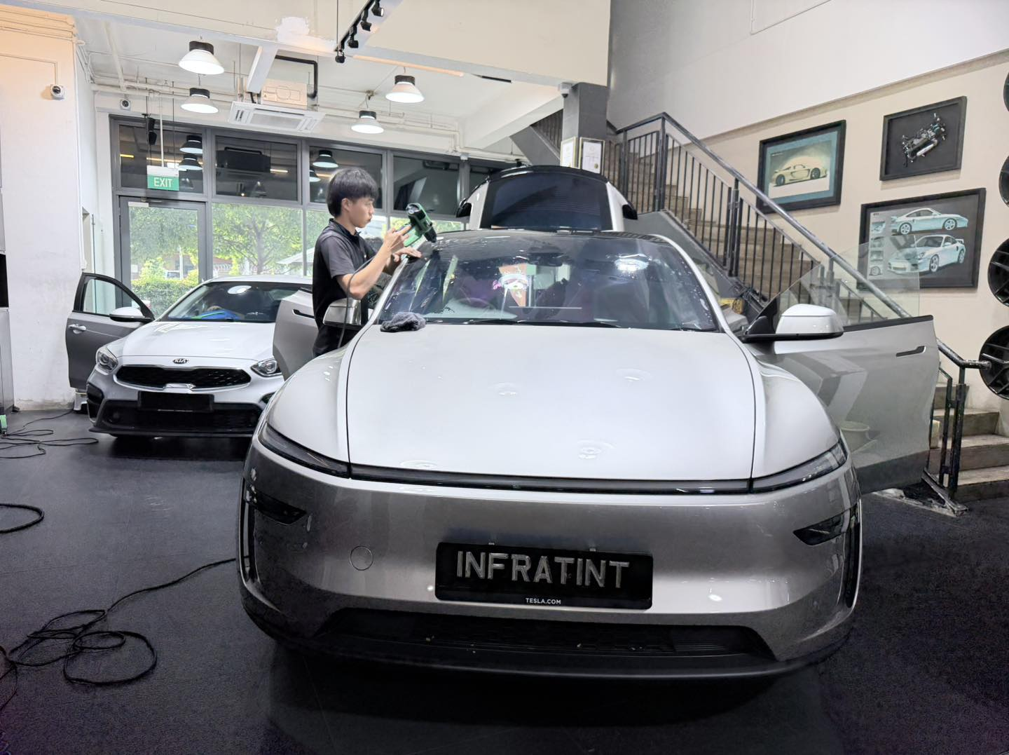 Infratint technician applying tint film to a Tesla in the workshop